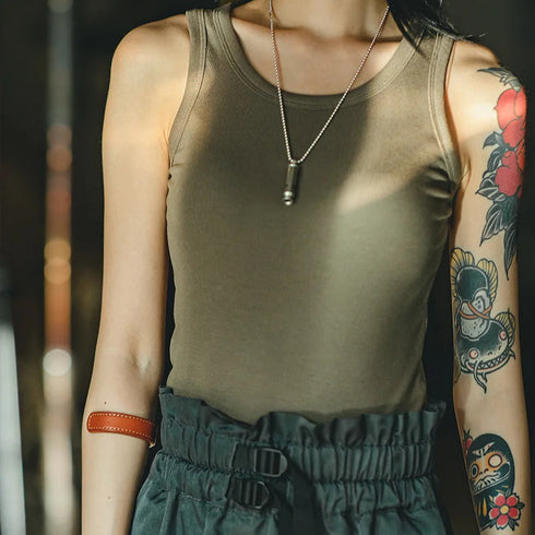 Person wearing a knitted vest with visible tattoos and jewelry.